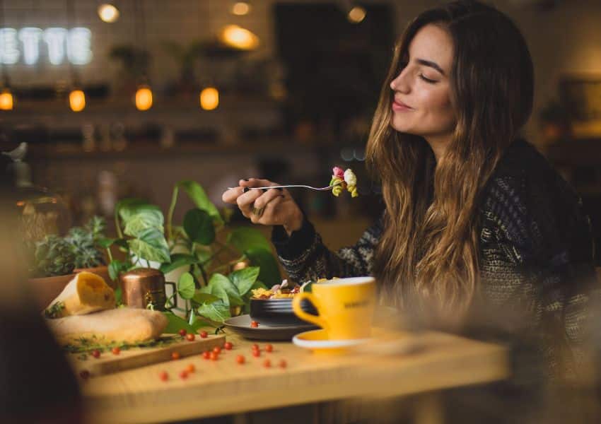 mulher comendo alimentos saudaeis na mesa