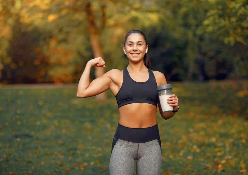 Mulher praticando esporte suplemento whey protein creatina top preto em um parque de outono