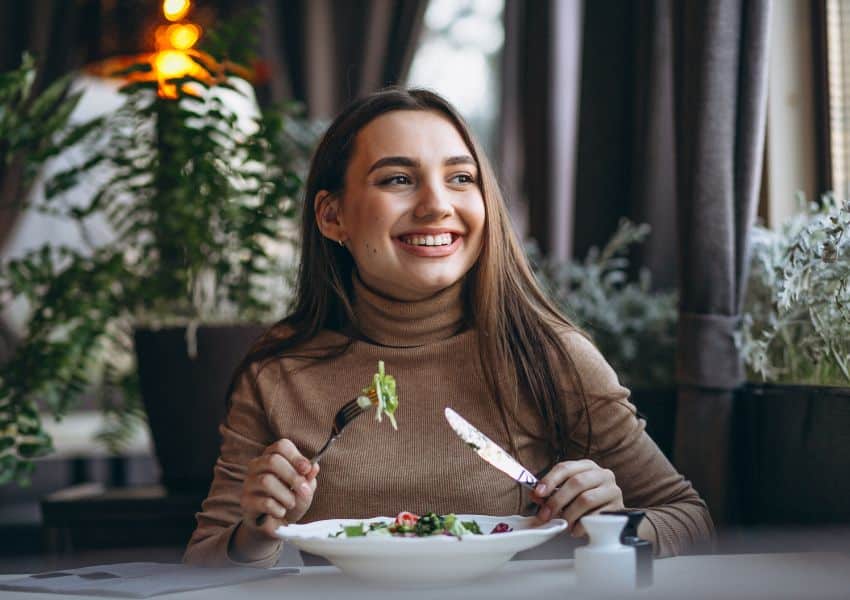 mulher jovem comendo salada em um restaurante ela usa flor de sal