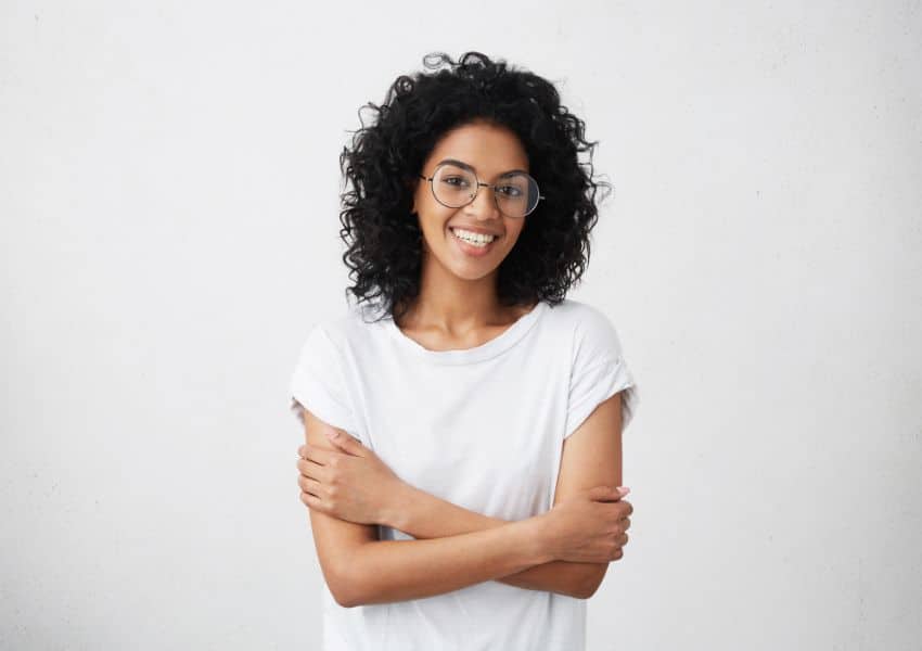 Mulher sorrindo usando óculos e camiseta branca