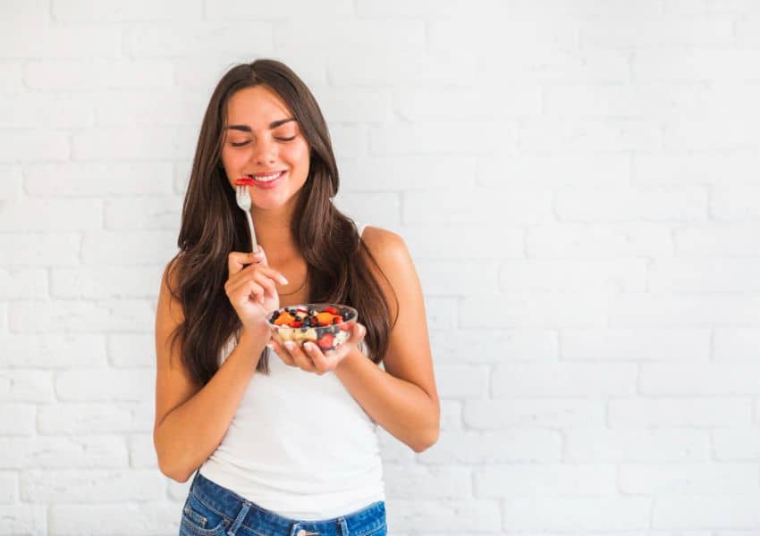 Mulher sorrindo comendo frutas morango