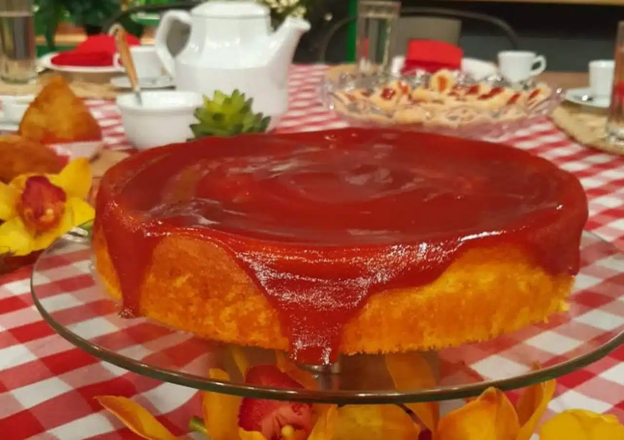 Fatia de bolo de milho cremoso coberta com calda de goiabada derretida, servida em prato rústico
