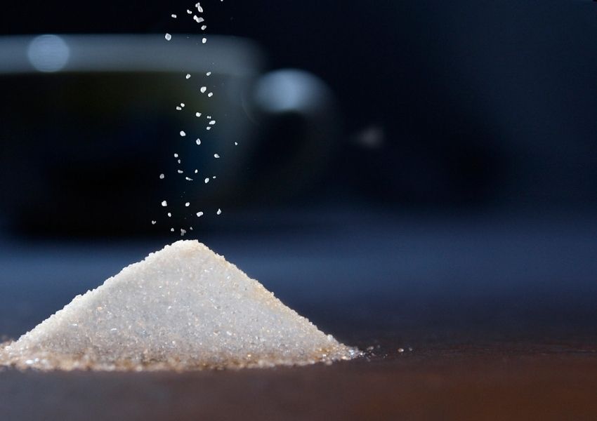 Montinho de Açúcar sendo colocado sopre a mesa. Os riscos do açúcar refinado. Como substituir o acucar.