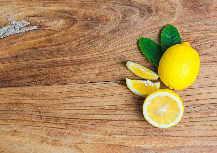 Conheça os benefícios do Limão. Um limão cortado ao meio e um limão enteiro sobre a mesa