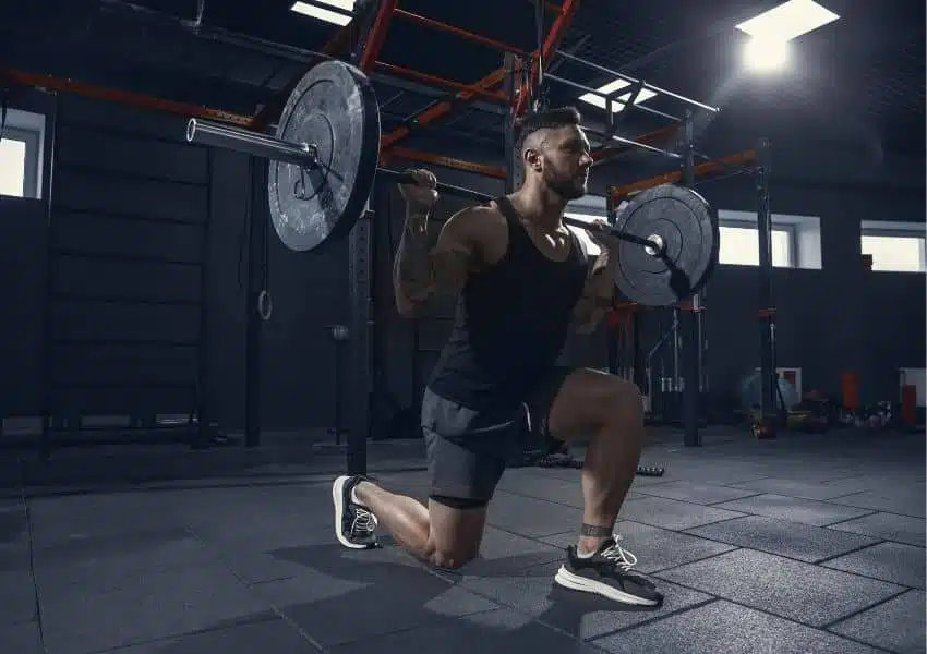 homem na academia malhando força barra suplementos