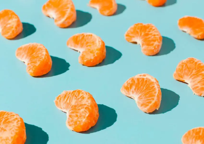 um grupo de laranjas descascadas sobre uma superfície azul.